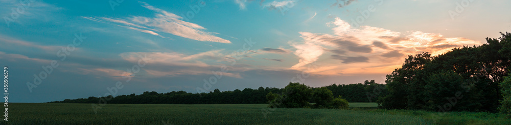 Panoramic large shot of sunset or sunrise over agricultural fields.