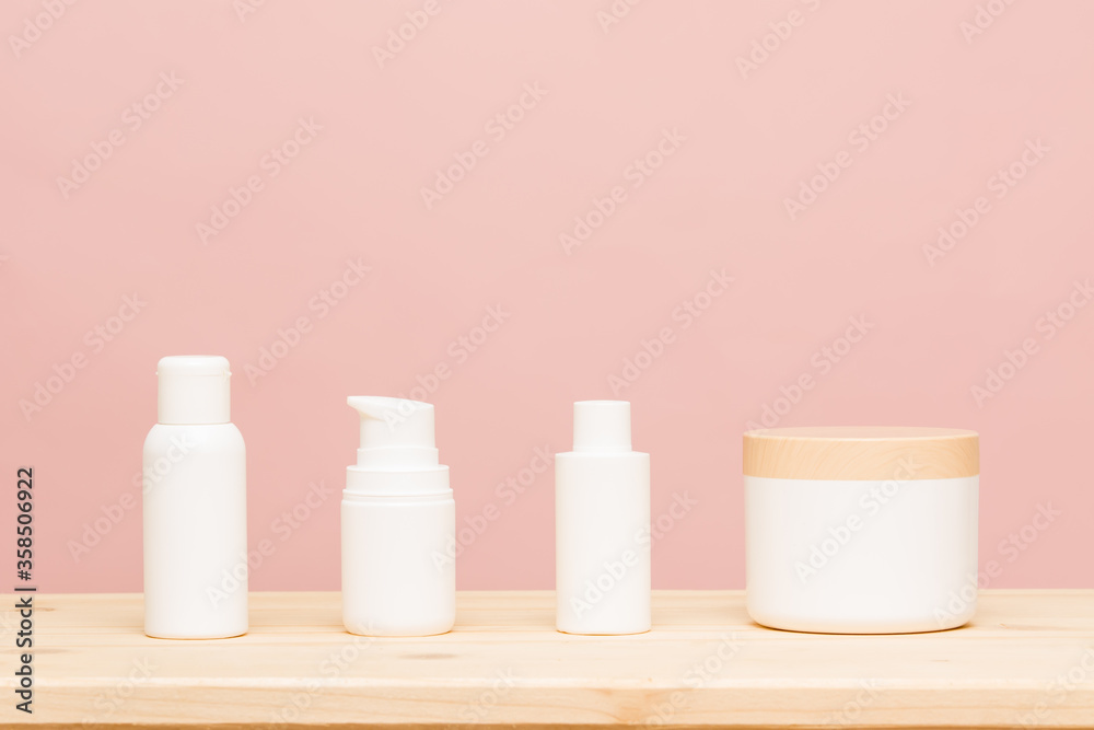 White cosmetic products on a pink background and wooden base. Natural cosmetics for branding mockup concept. Copy space.Healthy liftstyle concept White cosmetic products on a pink background and wooden base. Natural cosmetics for branding mockup concept. Copy space.Healthy liftstyle concept