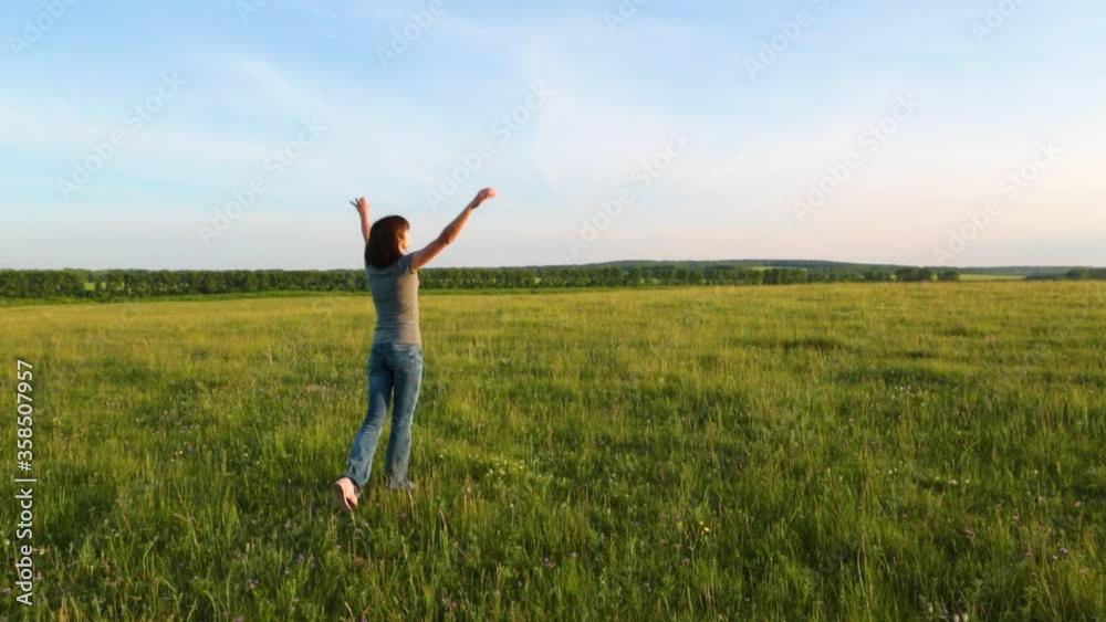 Woman at sunset raises her hands up and enjoys a beautiful warm sunny evening Woman at sunset raises her hands up and enjoys a beautiful warm sunny evening