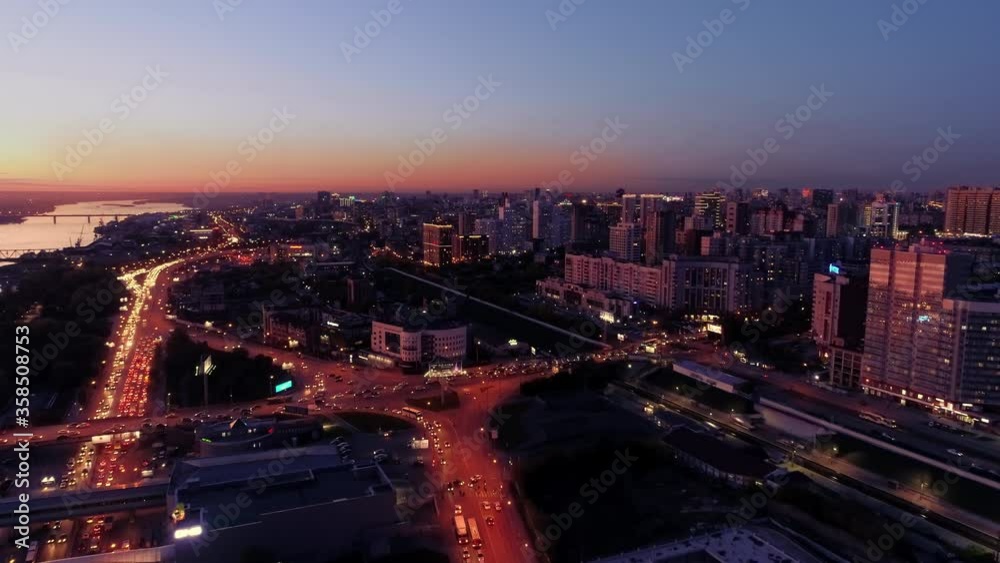 Beautiful sunset in the metropolis. Lights of the night city. Traffic flow in the evening. Evening cityscape after sunset. Modern city with buildings, roads and cars in twilight. Beautiful sunset in the metropolis. Lights of the night city. Traffic flow in the evening. Evening cityscape after sunset. Modern city with buildings, roads and cars in twilight.