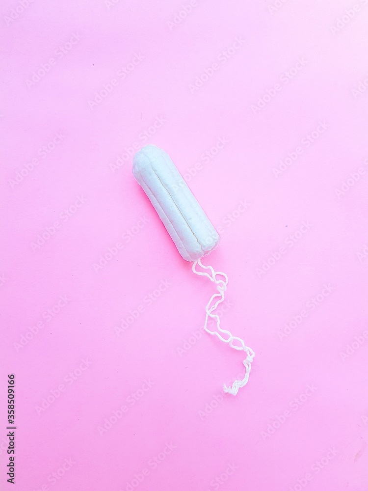 Women's hygiene intimate accessories. A clean white tampon on a pink background. Menstrual cycle. Space for text. Women's hygiene intimate accessories. A clean white tampon on a pink background. Menstrual cycle. Space for text.