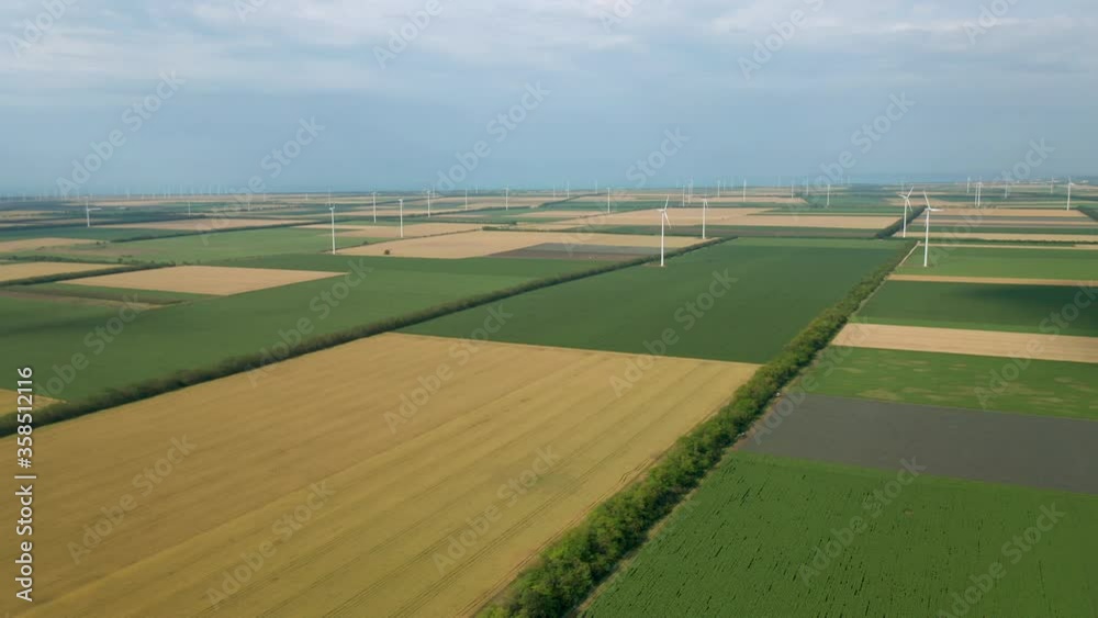 Aerial fly around wind turbines across spring agricultural field. Clean and Renewable Wind Power Farm in Motion. Green energy, sustainable alternative electricity, no pollution environment. Aerial fly around wind turbines across spring agricultural field. Clean and Renewable Wind Power Farm in Motion. Green energy, sustainable alternative electricity, no pollution environment.