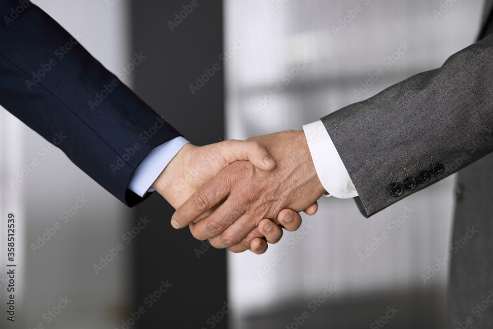 Business people in office suits standing and shaking hands, close-up. Business communication concept. Handshake and marketing Business people in office suits standing and shaking hands, close-up. Business communication concept. Handshake and marketing