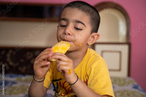 Happy little boy eating mango (lockdown activities)
