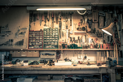 Complete workbench with a wall of tools in a workshop. Vintage look. photo