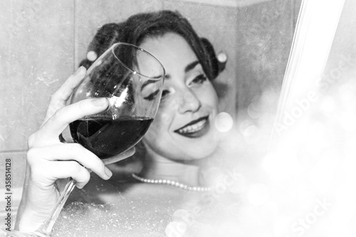 Photo of a girl with a glass and a book in the style of the 60s with the application of an aging and defocus filter.