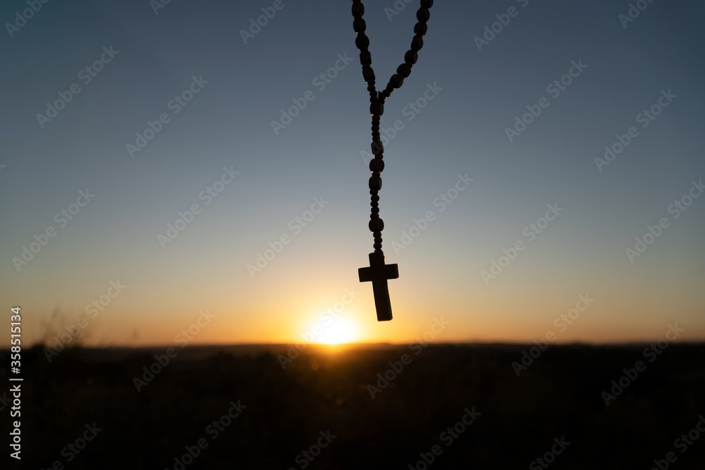 Silhouette of Religious cross on background of sun setting