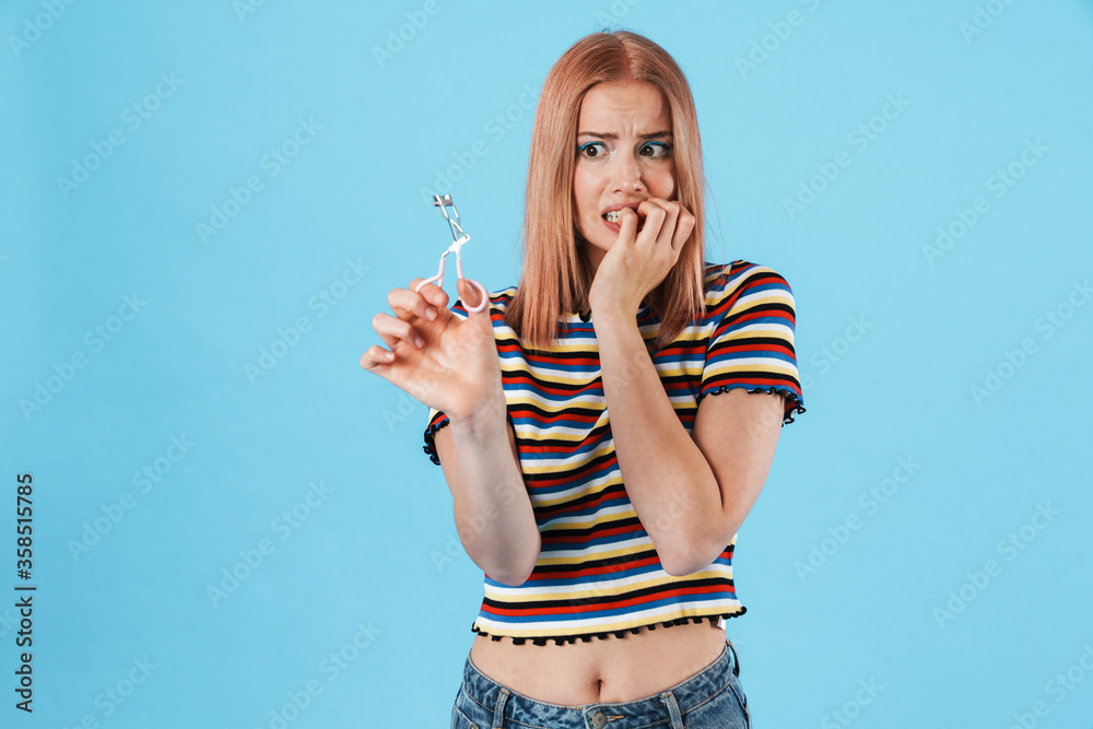 Image of beautiful scared woman posing with eyelashes curler Image of beautiful scared woman posing with eyelashes curler