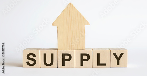 Wooden blocks with the word SUPPLY , house. The concept of the high cost of rent for an apartment or home. Interest rates are rising. Real estate market.