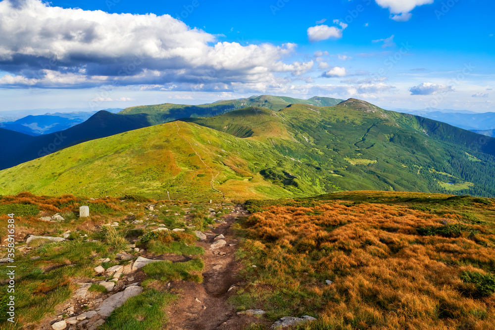 Carpathian mountain path hiking or trekking moody landscape valley panorama, summer nature outdoor road view. Adventure tourism scenic way trail. Blue sky and clouds, sunny beautiful day.