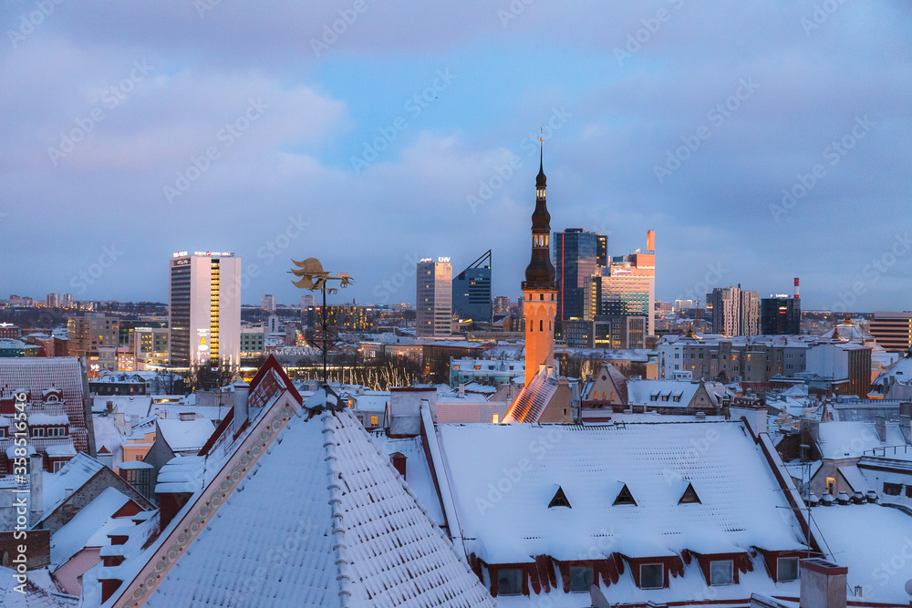 Fototapeta premium TALLINN, ESTONIA - DECEMBER 26, 2018: Roof and tower of old town. Winter panoramic aerial view by evening.