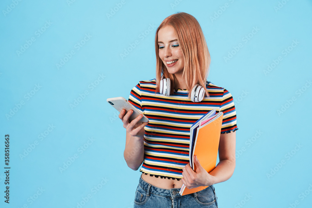 Image of happy woman using cellphone while holding exercise books Image of happy woman using cellphone while holding exercise books