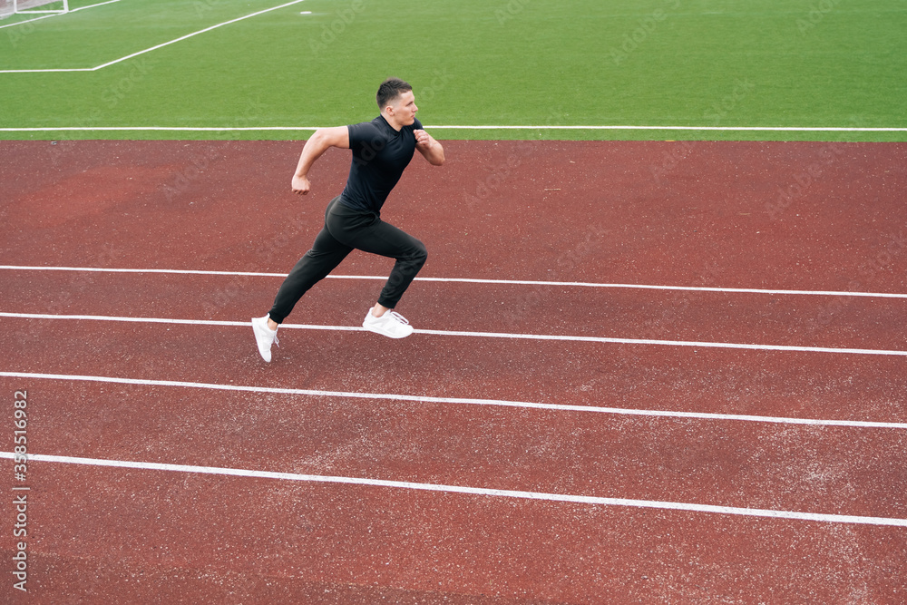 Obraz premium The sprinter started accelerating while running. A man is engaged in athletics on a red treadmill. Sports ground with a special coating for the athlete