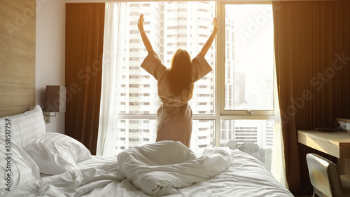 Canvas-taulu long dark haired girl in beige bathrobe awakes and stretching near large window