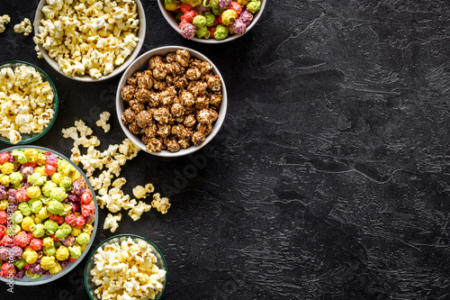 Foto Set of flavored popcorn and soda on black desk top-down space for text
