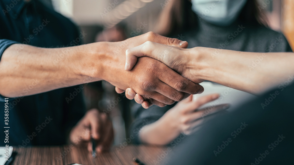 business man in a protective mask squeezing the hand of his colleague.