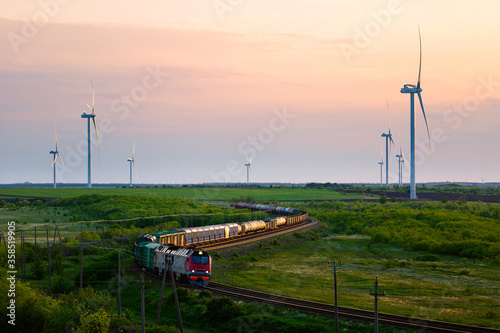 Wind farm and moving train at sunset