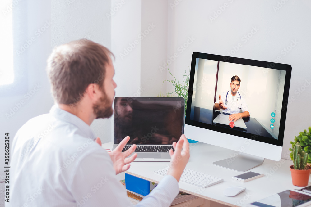 Man talking to his doctor through videoconference on the computer at home