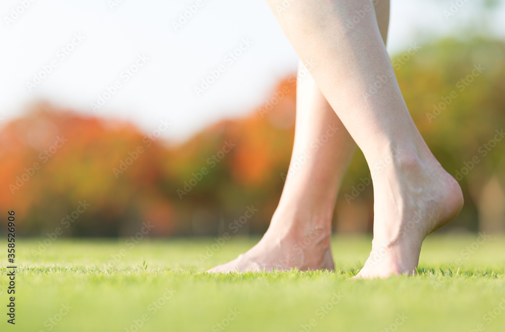 Closeup of caucasian woman's bare feet walking barefoot on the soft green grass at a park during autumn. Closeup of caucasian woman's bare feet walking barefoot on the soft green grass at a park during autumn.