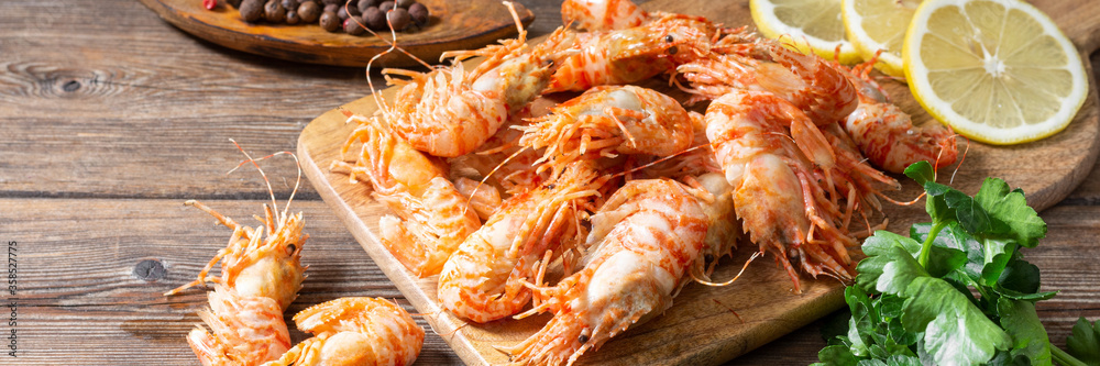 Shrimp on a wooden Board on a brown wooden table. Greenlandic prawns. Banner