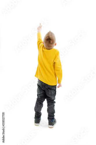 Back view of little boy points at wall. Rear view. Isolated on white background 
