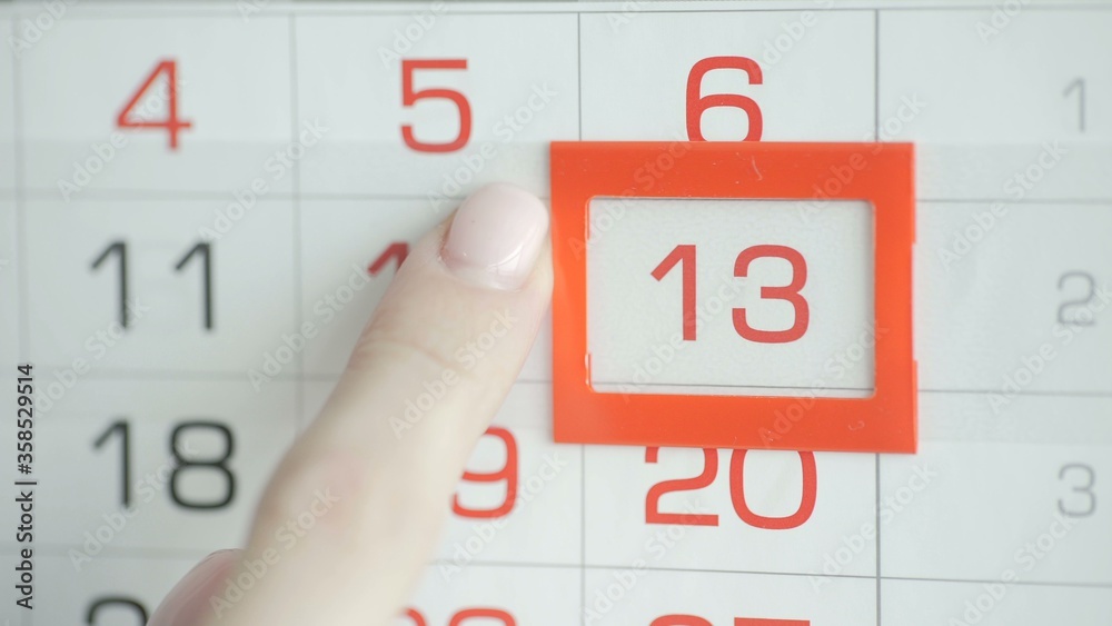 Woman's hand in office changes date at wall calendar. 13 Woman's hand in office changes date at wall calendar. 13