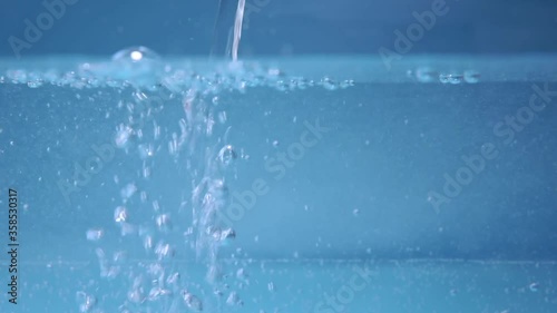 Close-up of a glass of water on a blue background. close up of bubbles macro