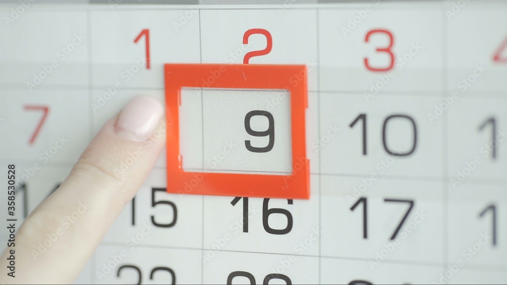 Woman's hand in office changes date at wall calendar. 9 Woman's hand in office changes date at wall calendar. 9