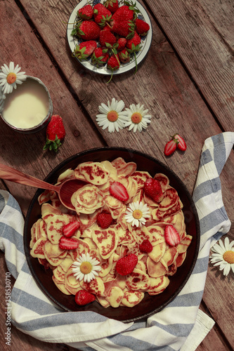 Pancake cereal with strawberries. Mini pancakes in a pan. Strawberry pastries