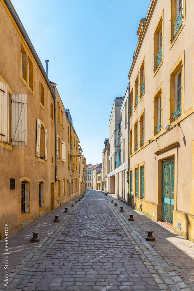 Narrow cobble stone street with yellow buildings in Metz, France