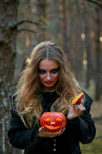 girl witch witch pumpkin on halloween in a dark pine forest
