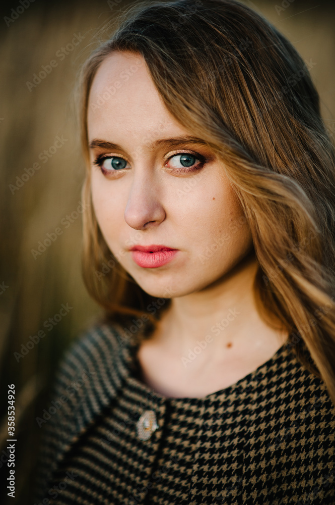 Naklejka premium Portrait of a beautiful girl in autumn on the background the nature. upper half length. Close up. looking at the camera.