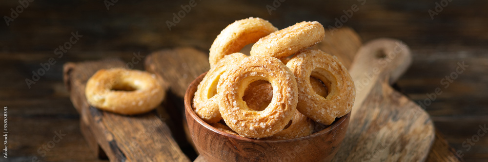 Puff pastry sprinkle with sugar in a wooden bowl on a brown wooden background. Cookies sprinkle with sugar close-up. Sweet pastries. Banner Puff pastry sprinkle with sugar in a wooden bowl on a brown wooden background. Cookies sprinkle with sugar close-up. Sweet pastries. Banner