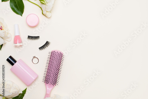 Beauty flat lay with cosmetic products and flowers on light background with copy space. Top view