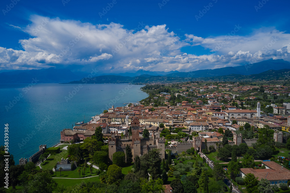 Fototapeta premium Lazise, Lake Garda, Italy. Aerial view of the historic part of Scaliger Castle of Lazise in the background cumulus clouds in the blue sky