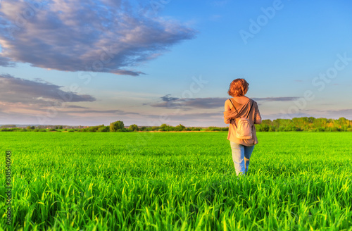 Young woman walking in field at sunset time