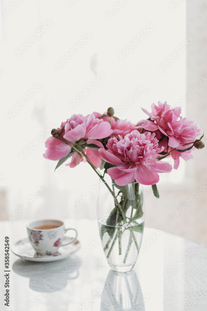pink peonies on the table with a cup of tea pink peonies on the table with a cup of tea