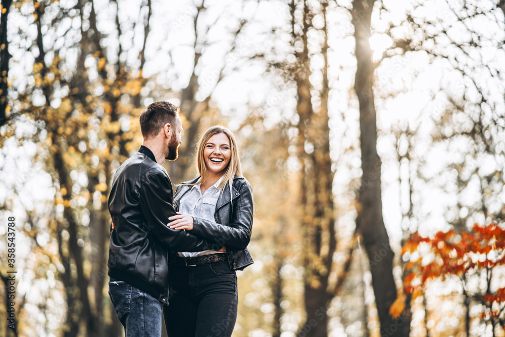 Beautiful young couple walking in the autumn park on a sunny day Beautiful young couple walking in the autumn park on a sunny day