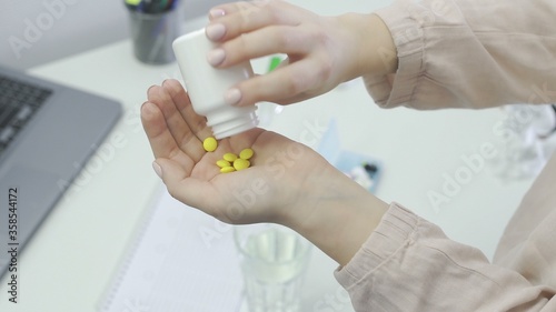 Woman takes and shows pills vitamins or drugs tablets in hand from pill bottle