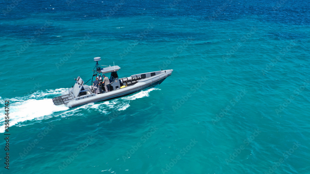 Naklejka premium Aerial drone photo of luxury inflatable speed boat cruising in deep blue Aegean sea, Mykonos island, Cyclades, Greece