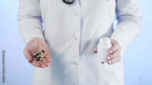 Doctor pours pills out of the bottle on a blue background