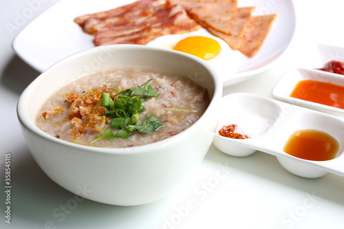 Rice Porridge, ham, bacon, fried egg, served with various sauces Put on the white table Ready to eat