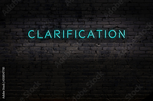 Night view of neon sign on brick wall with inscription clarification