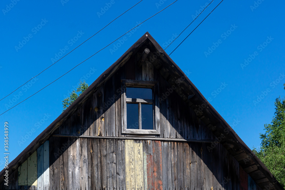 Upper part of an old wooden village house with a gable roof and a window