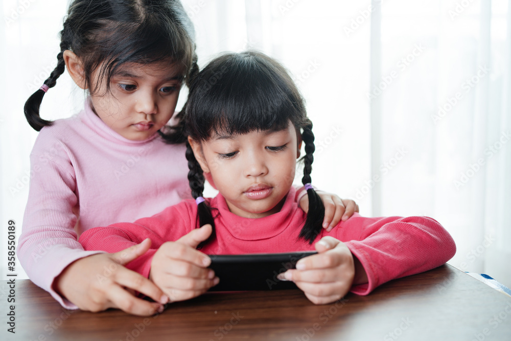 sisters playing with tablets and smartphone. Technology concept.