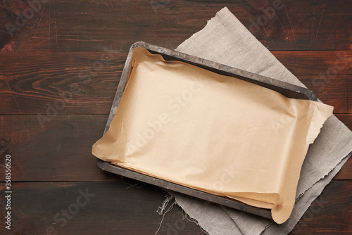 Obraz na płótnie empty rectangular metal pan covered with brown parchment paper on a wooden table
