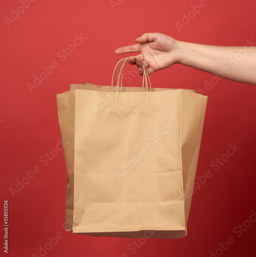female hand holds a paper bag from brown craft paper