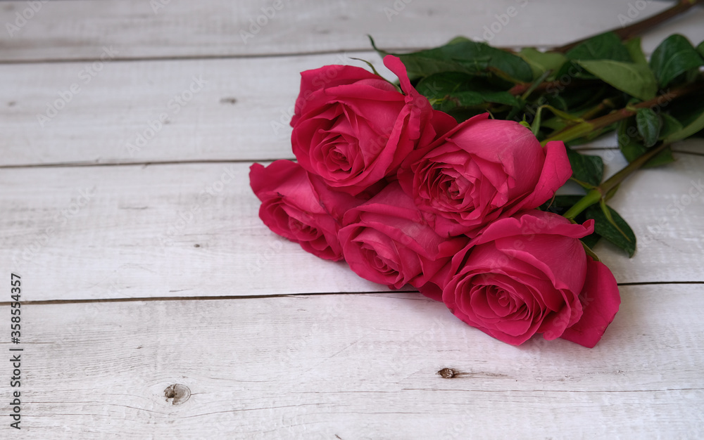 Red pink bouquet of roses on a wooden background with a place for text