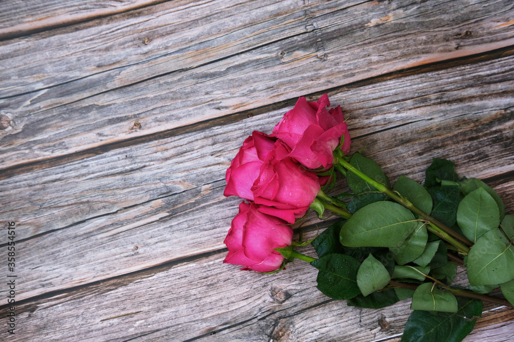 Red pink bouquet of roses on a wooden background with a place for text