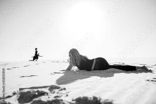 young couple a guy and a girl with joyful emotions in black clothes walk through the white desert
